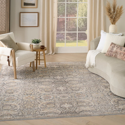 Neutral living room with beige-gray ornate rug, cream curved sofa, light-wood chair, round side table, framed art, pampas grass by a large window.