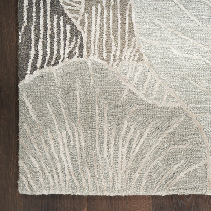 Neutral gray-beige area rug with abstract leaf pattern in textured pile on dark wood floor.