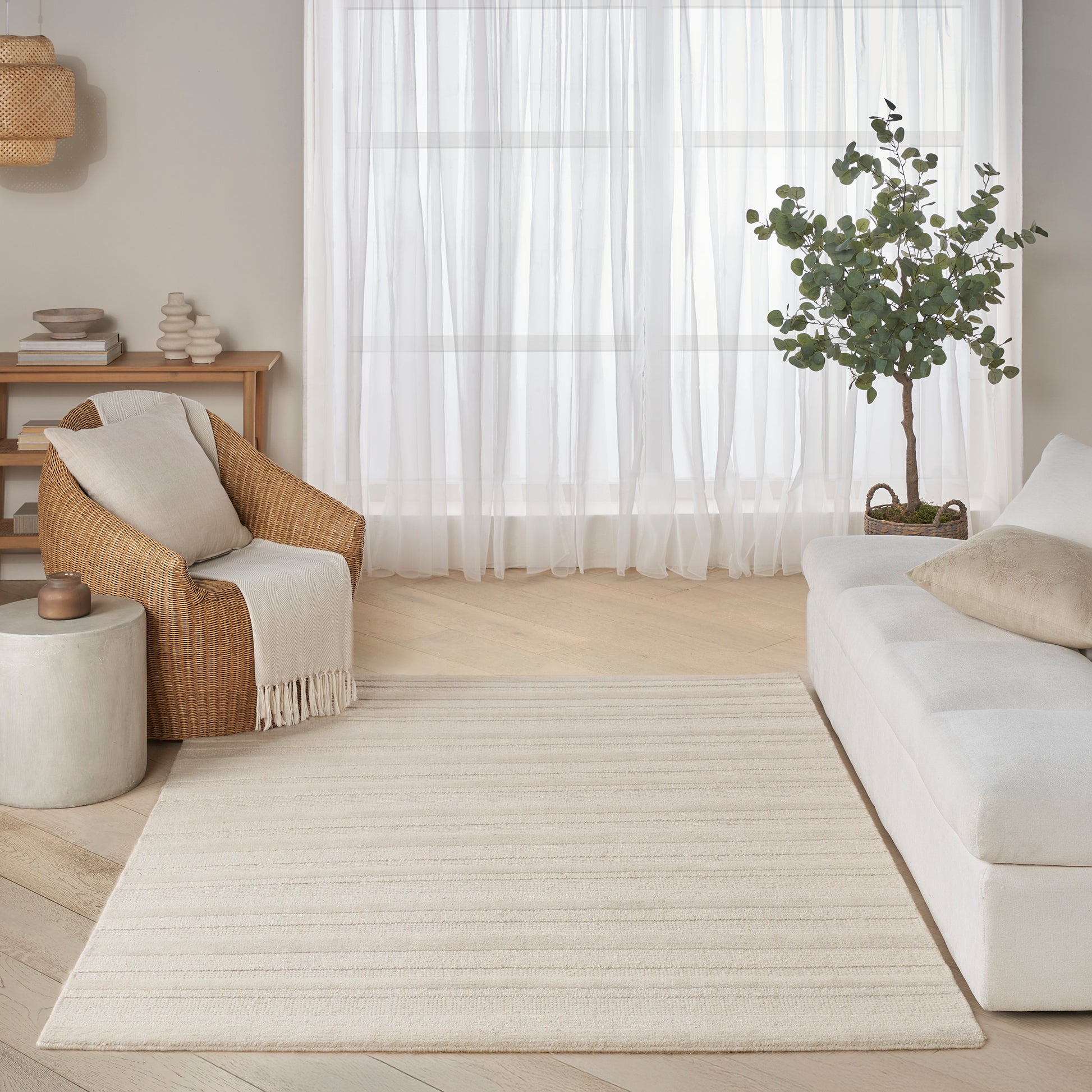 Beige rectangular rug with subtle striped texture in a light, minimalist living room setting.