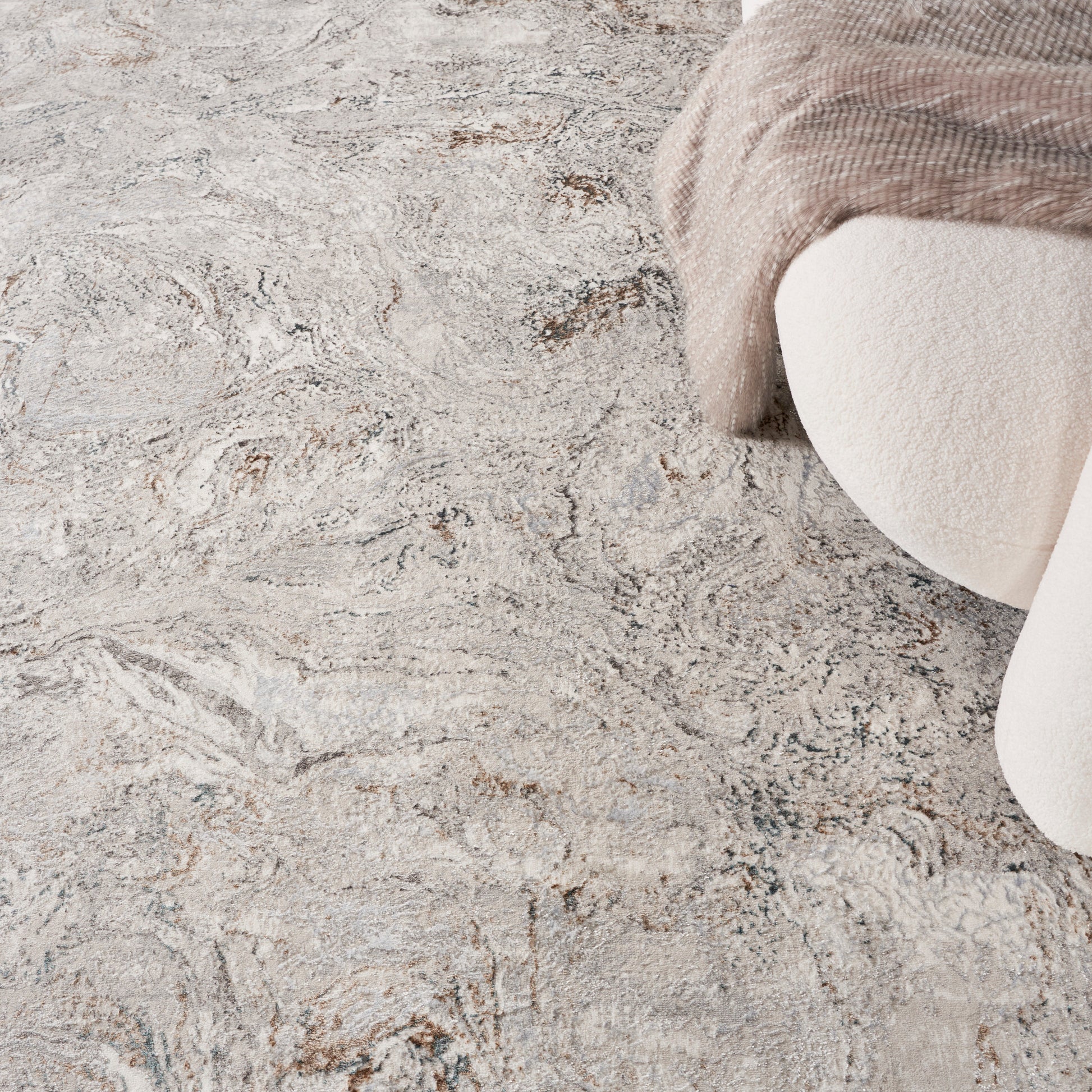 Beige-gray marbled area rug with soft texture, paired with cream upholstery and a taupe knit blanket draped over.