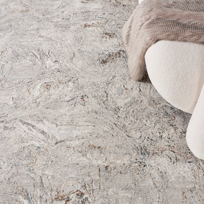Beige-gray marbled area rug with soft texture, paired with cream upholstery and a taupe knit blanket draped over.