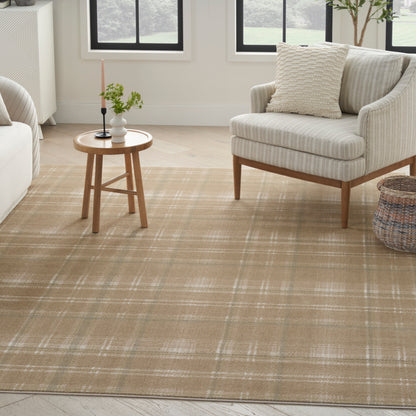 Neutral living room with beige plaid area rug, light fabric armchair, round wooden side table, candle, plant.