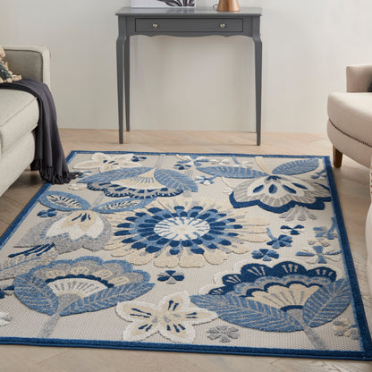 Blue floral patterned area rug with beige backdrop and dark blue border in a living room beside a gray console table.