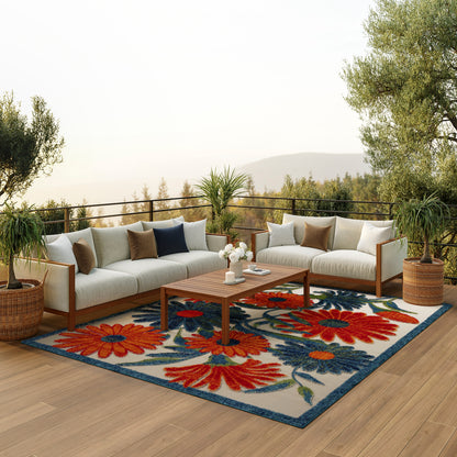 Outdoor rug on wooden deck with a beige cushioned sectional, coffee table and potted plants