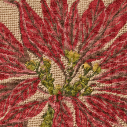 Close-up of a red floral tapestry with a beige background, woven texture, and a green-yellow center.