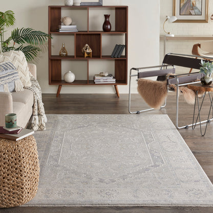Cozy living room with dark wood cubed bookshelf, light gray rug, beige sofa, woven ottoman, and a metal-framed chair.
