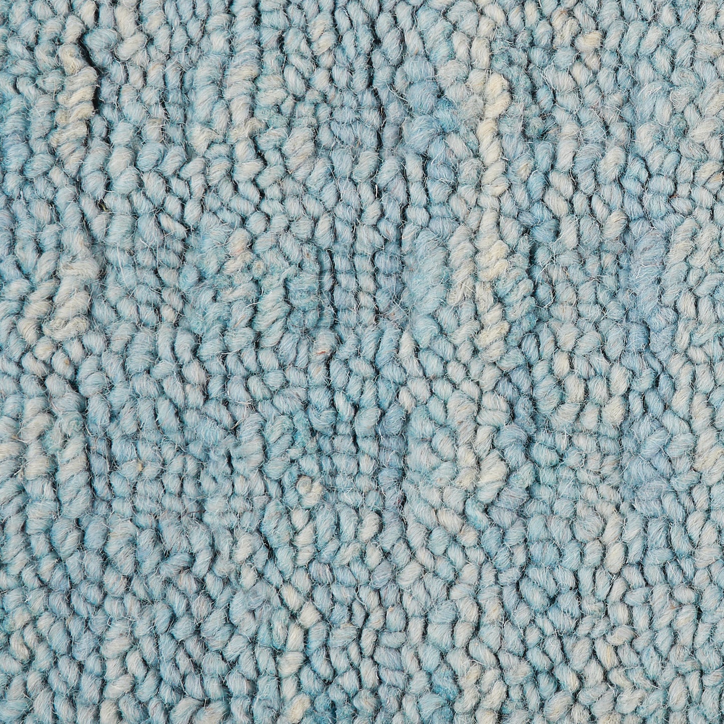 Close-up of blue shaggy rug pile with cream highlights; soft, textured, plush loops.