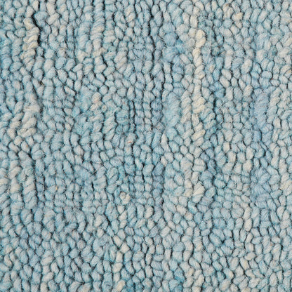 Close-up of blue shaggy rug pile with cream highlights; soft, textured, plush loops.