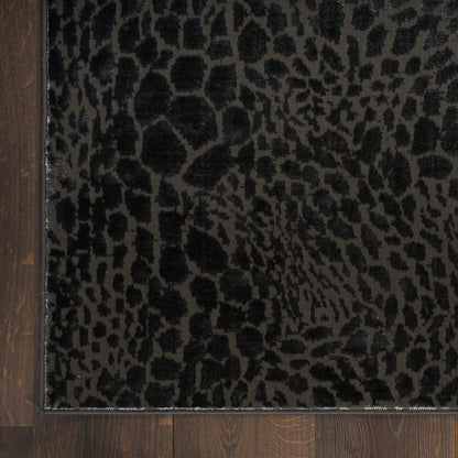Leopard-print rug in dark charcoal and black, low-pile plush texture, bordered edge on wood floor.
