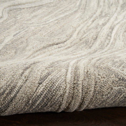 Beige plush rug with soft, textured loop-pile in wavy patterns, folded over dark wooden floor.