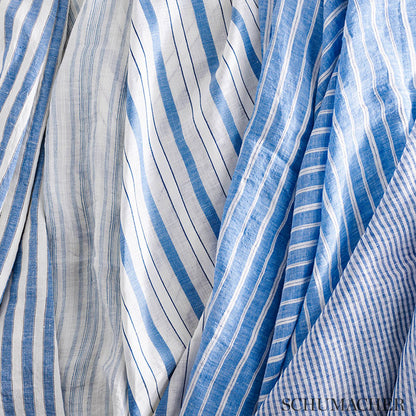 Blue and white striped linen fabrics, varying stripe widths, draped to show breathable, lightweight summer textiles.
