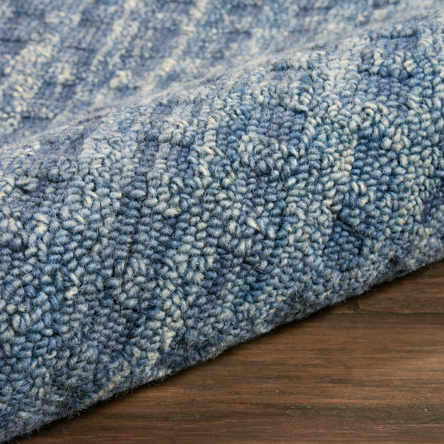 Blue textured runner rug with loop pile and variegated light and dark blue tones on a wooden floor.