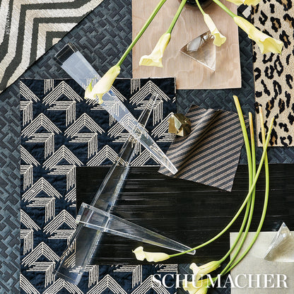 Flat lay of navy geometric fabric swatches, clear acrylic prisms, wood tile, leopard print rug edge, and yellow calla lilies.
