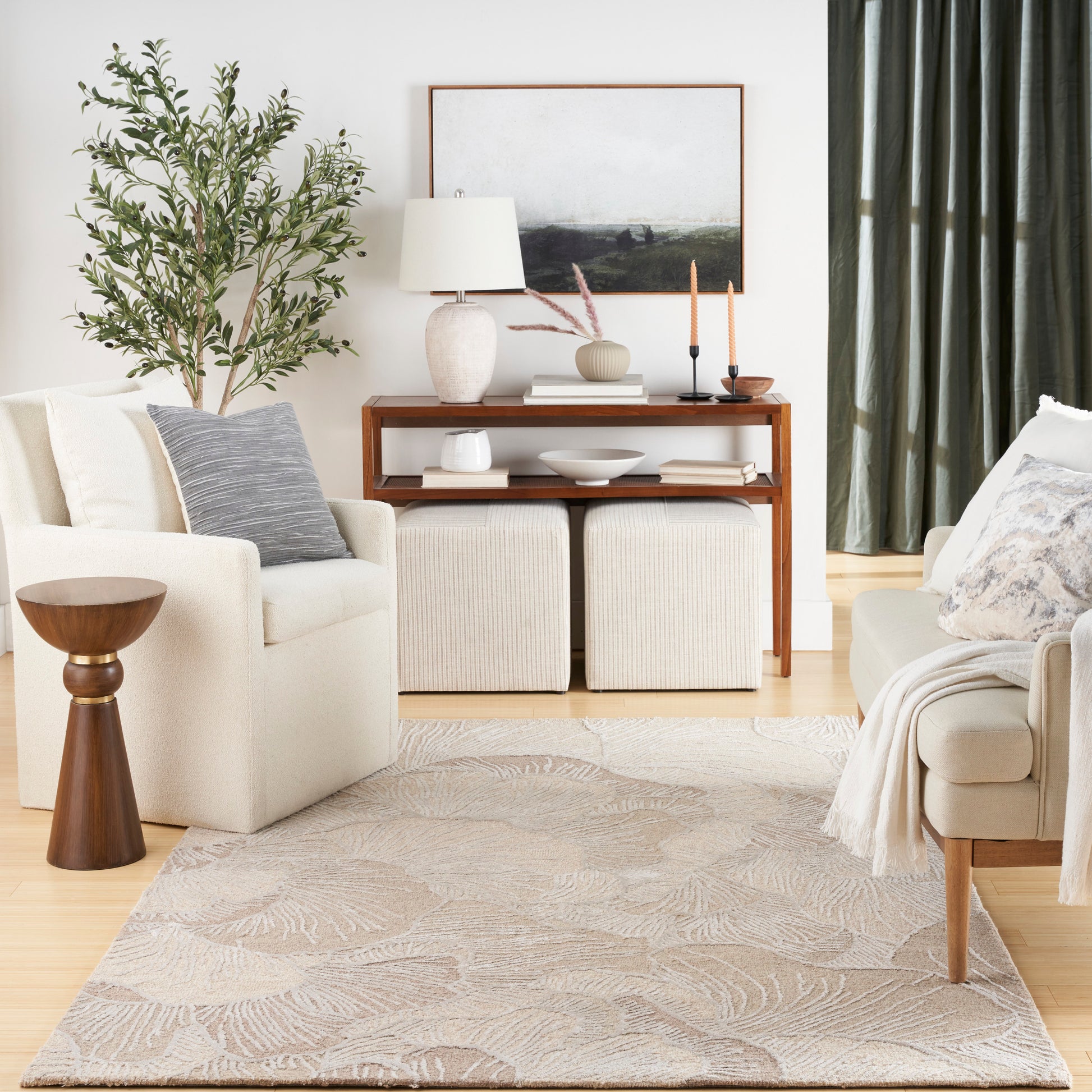 Neutral living room with beige sofa, armchair, wooden console, plant, leaf-pattern rug, cream ottomans, and green curtains.