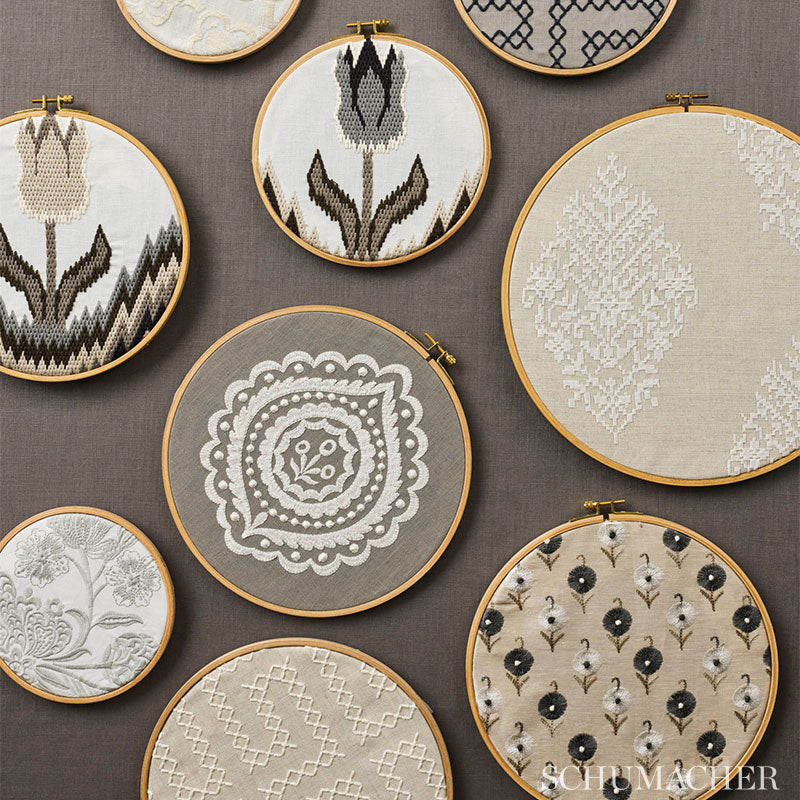 Assorted embroidery hoops with beige, gray and white floral and geometric patterns on a brown background.