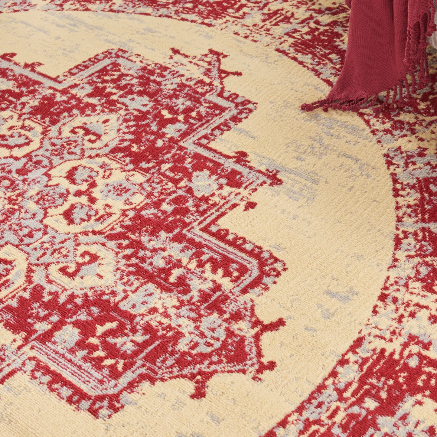 Red and ivory oriental round rug with intricate floral border and tassel fringe.
