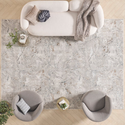 Overhead view of a neutral living room with a large marbled gray rug, cream sofa with knit throw, and two round gray chairs.