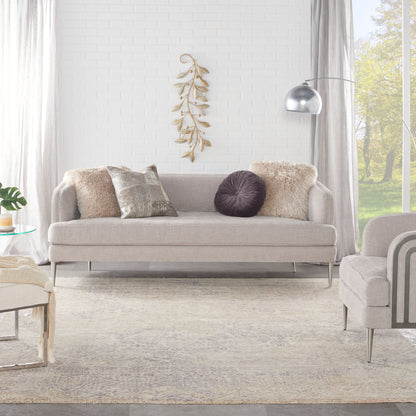 Vintage 8' x 10' rug in light gray on the floor of a modern living room, with an arc floor lamp, white brick wall, and dried leaf art.