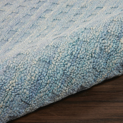 Soft blue and white variegated shag runner with thick plush pile, rolled edge on dark wood floor.