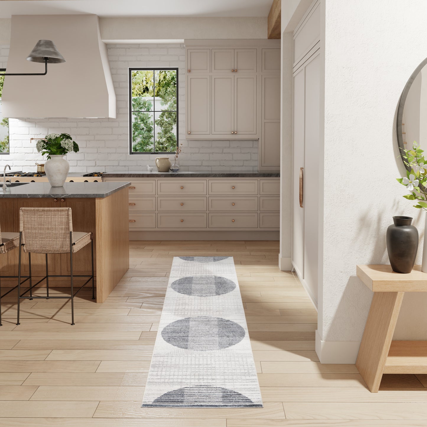 Bright white kitchen with light wood floors, island seating, white cabinets, and a long gray circular-patterned runner rug.