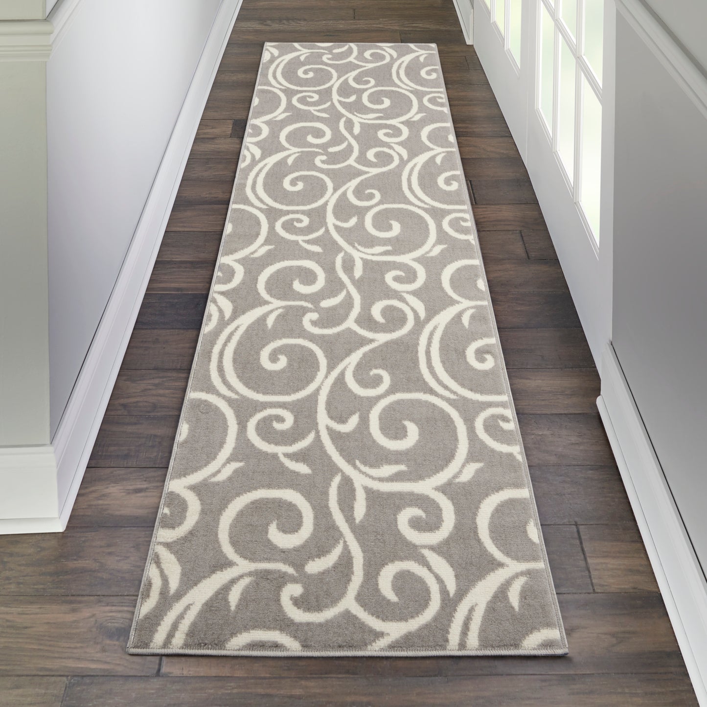 Gray hallway runner rug with white swirling scroll pattern; long rectangular rug for a wood-floored hall
