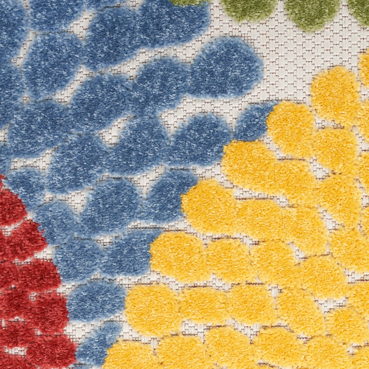 Close-up of tufted rug showing blue & yellow floral clusters on beige background; red edge visible.