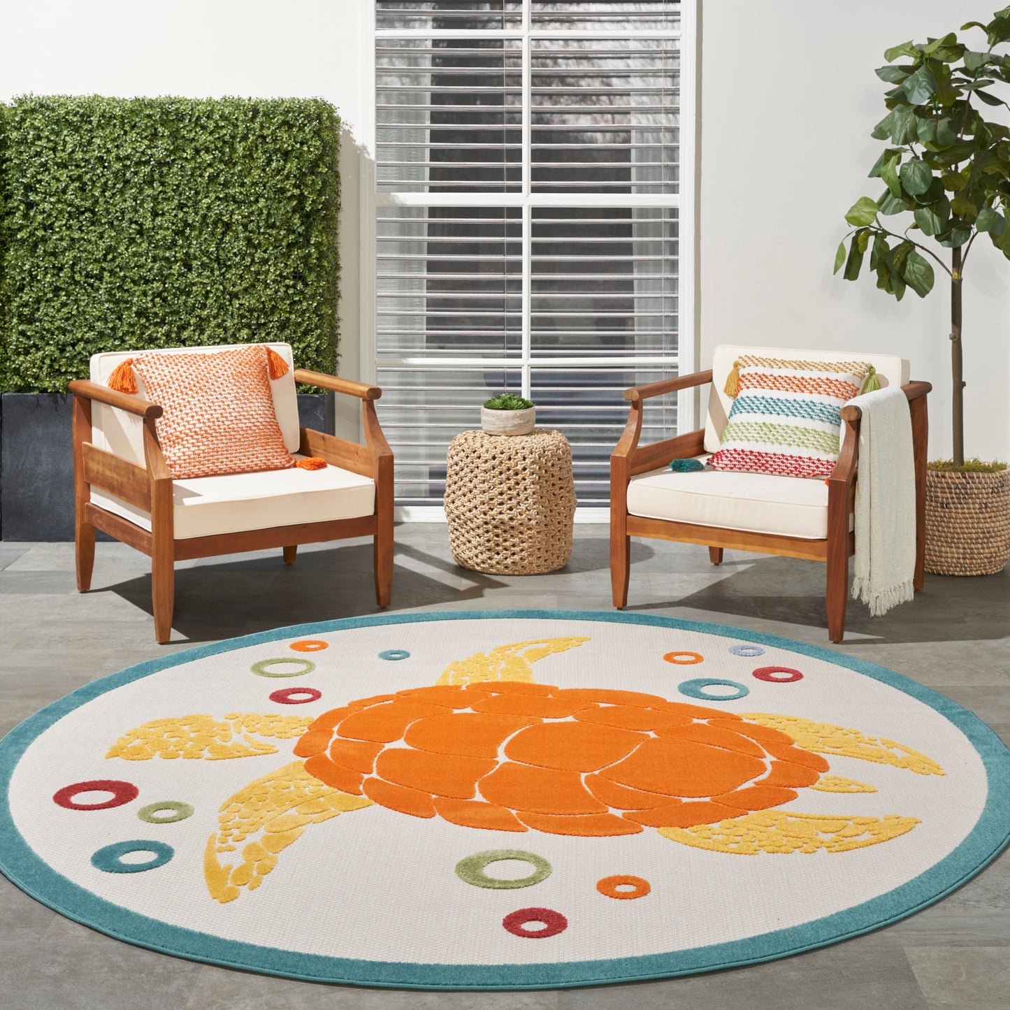 Round outdoor rug featuring a large orange sea turtle with teal border & colorful rings.