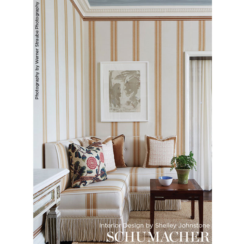 Cobalt striped wallpaper, white fringe sofa, floral and solid cushions, dark wood coffee table, plant, framed abstract art.