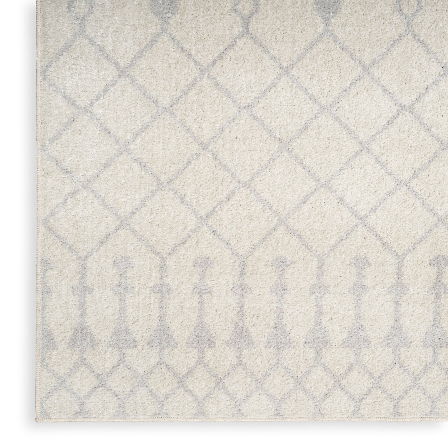 Cream rug with pale gray lattice pattern and subtle arched border; soft, textured surface.