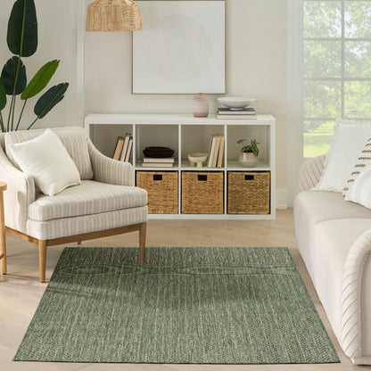 Neutral living room with sage green woven rug, beige striped armchair, white cubby shelf with wicker baskets, plants.