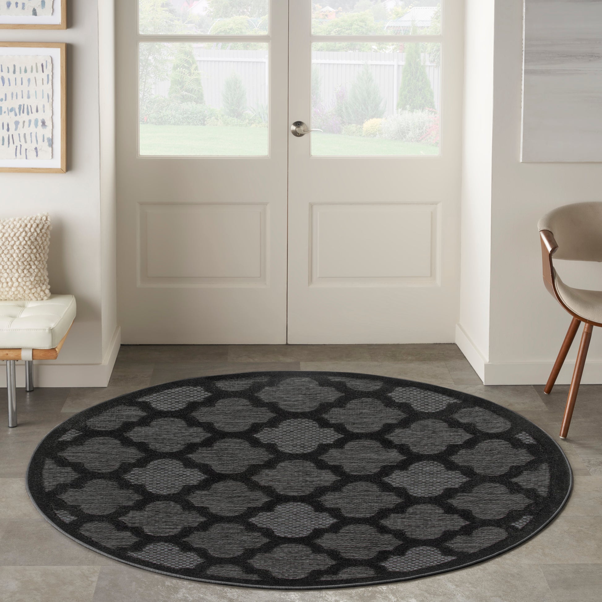 Round rug with dark gray background and light gray quatrefoil lattice pattern in a modern entryway.