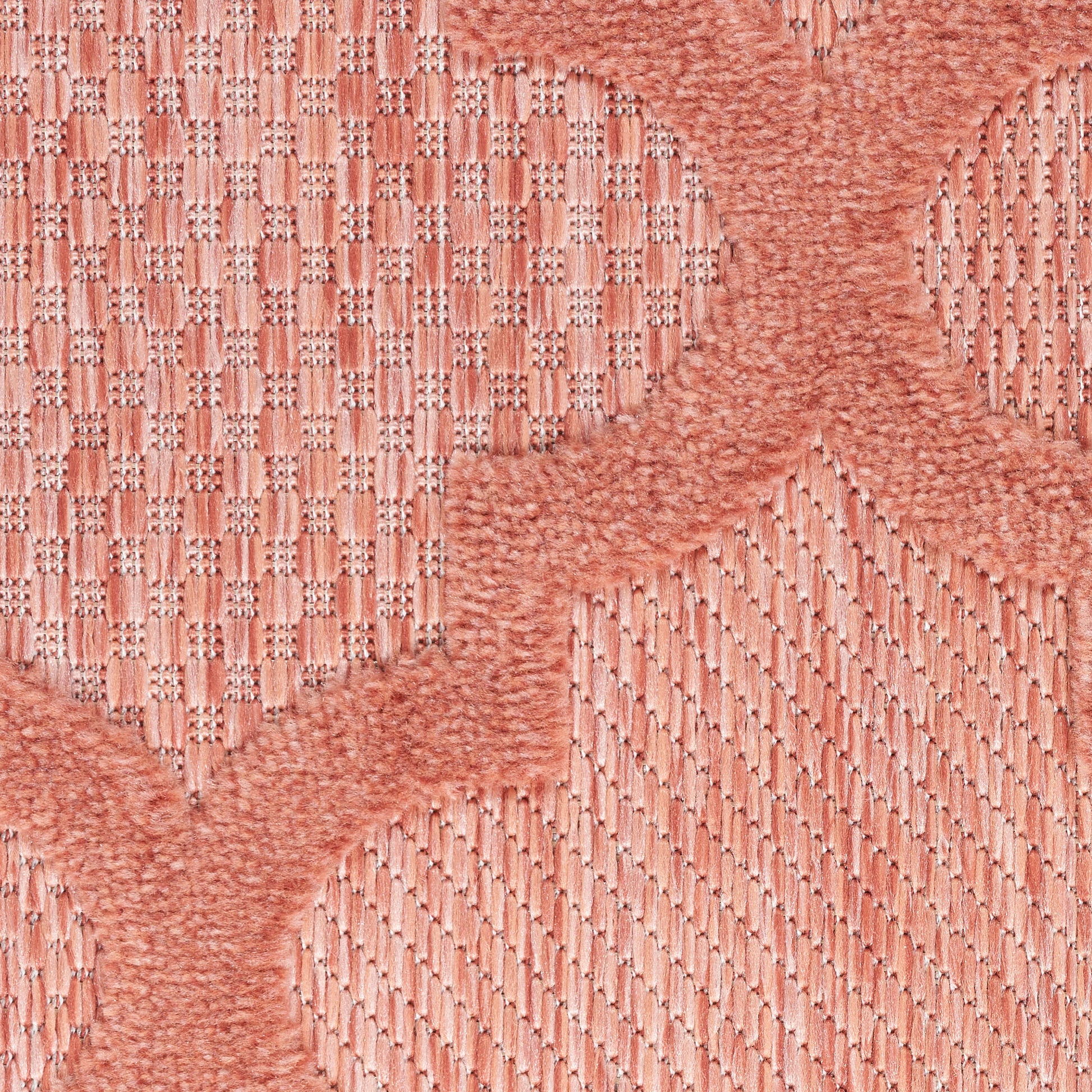 Peach-pink woven textile with circular raised motifs and wavy borders; soft rug or upholstery fabric.