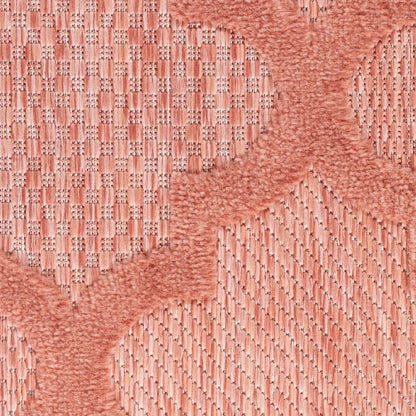 Peach-pink woven textile with circular raised motifs and wavy borders; soft rug or upholstery fabric.