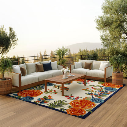 Outdoor patio with white cushioned sectional sofa on a floral rug; wooden coffee table; potted plants; hills.