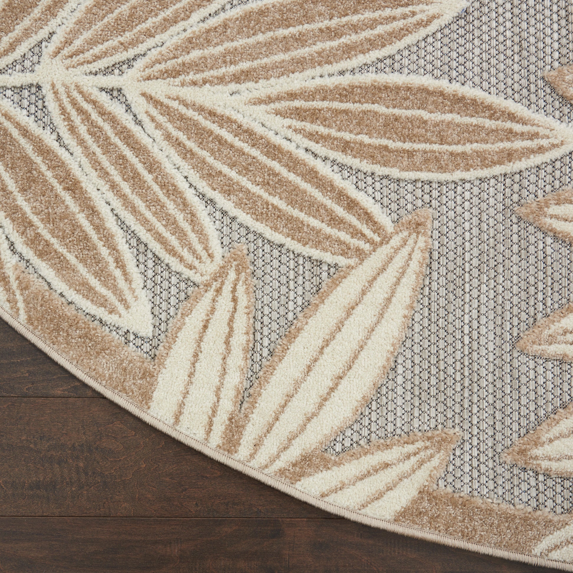 Round area rug with beige leaf pattern on gray lattice background; woven texture, modern neutral decor.