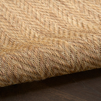 Natural beige woven jute rug with zigzag chevron pattern, thick textured fibers on dark wooden floor.