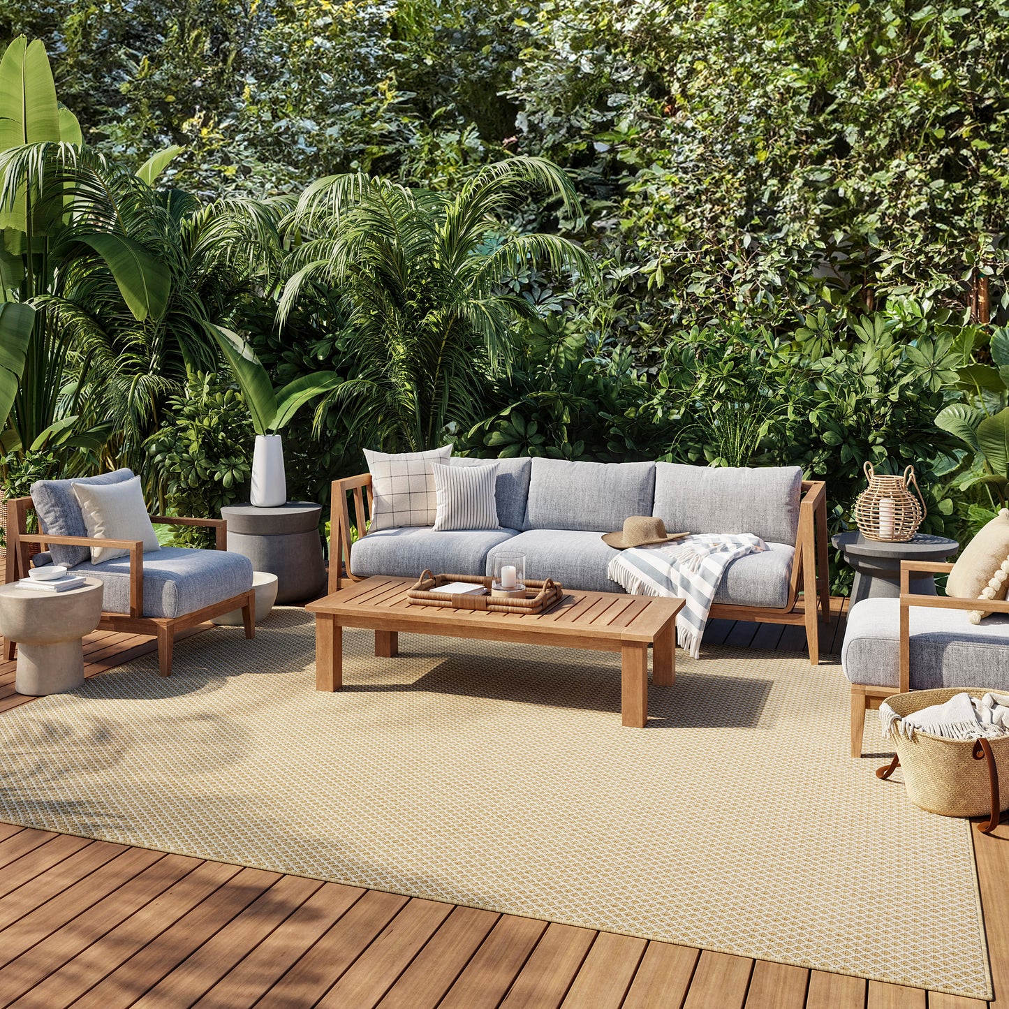 Outdoor patio lounge set with gray cushioned sofas and chairs, wooden frames on a beige rug amid lush tropical plants.
