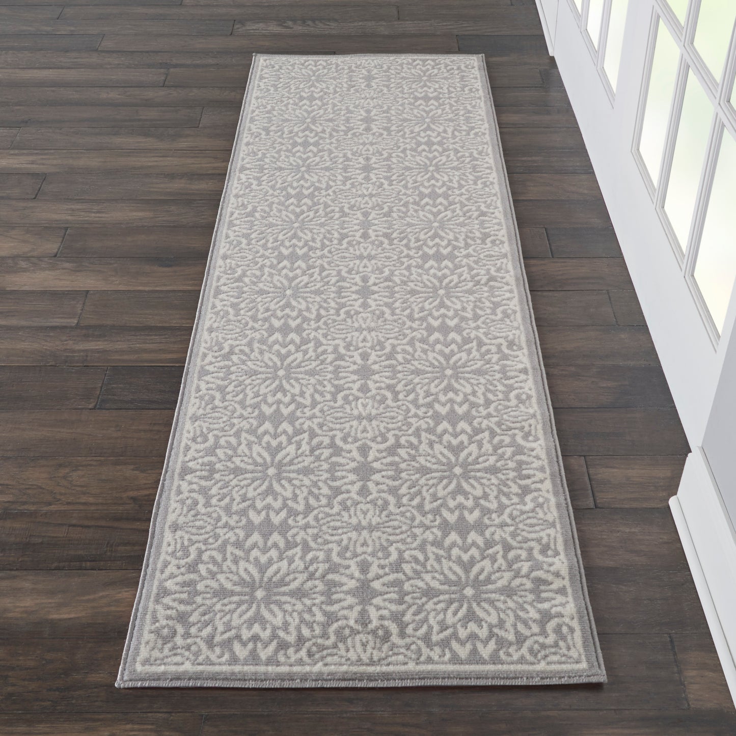 Long hallway runner rug in gray and ivory floral damask pattern with a light border.