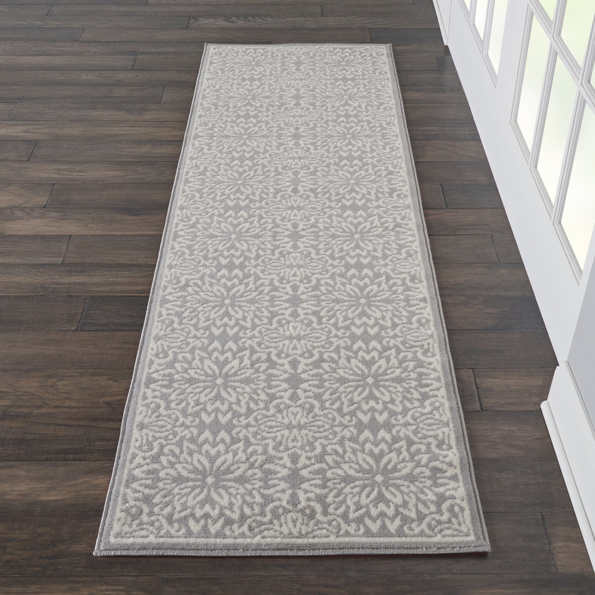Long hallway runner rug in gray and ivory floral damask pattern with a light border.
