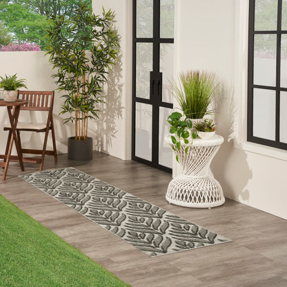Modern entry with gray leaf-pattern runner rug, white wicker planter, tall potted tree, chair, black-framed glass doors.