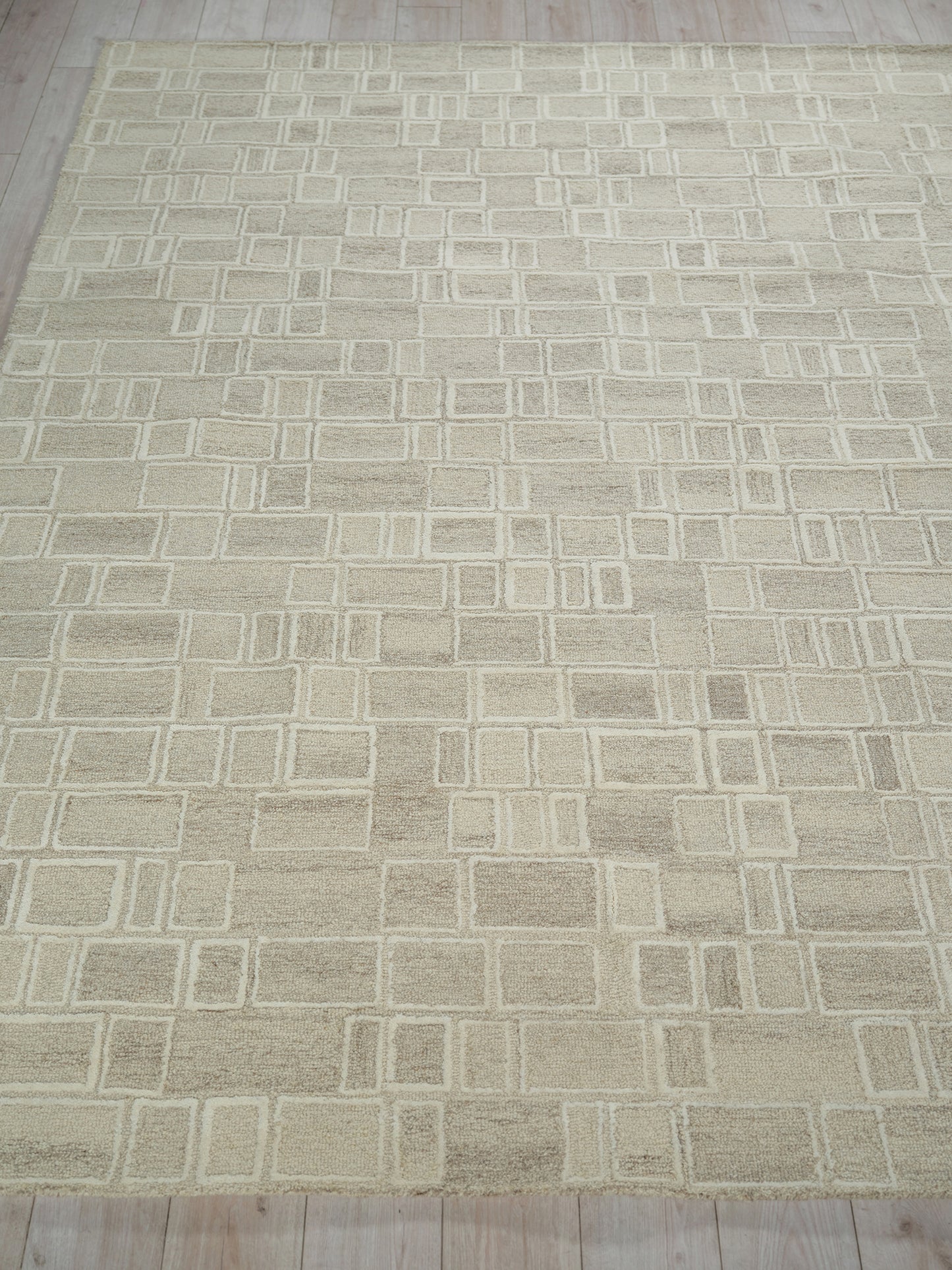 Beige area rug with cream geometric grid of squares and rectangles, soft textured look, modern living room decor.