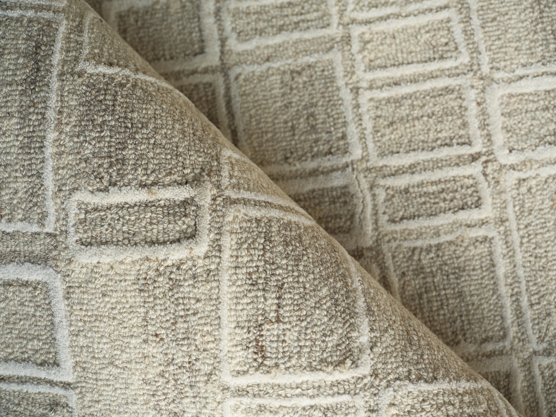Beige tufted rug with square grid pattern, plush texture, folded corner.