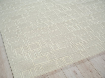 Cream textured rug with geometric outlined rectangles on light wood floor.