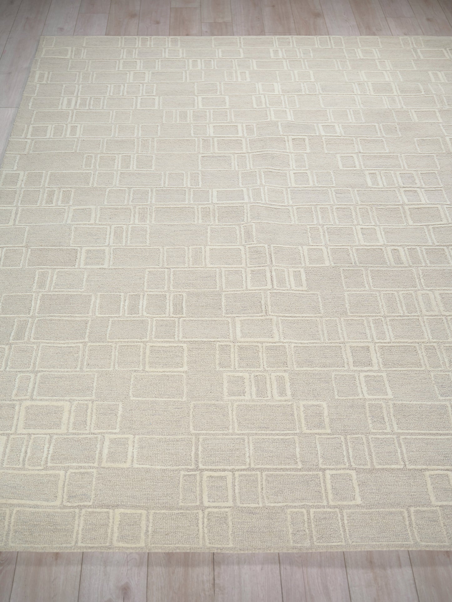 Cream rectangular rug with a modern geometric grid of square outlines in pale cream tones.