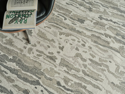 Abstract gray-beige rug with a black leather round chair and an open notebook showing a green illustration.