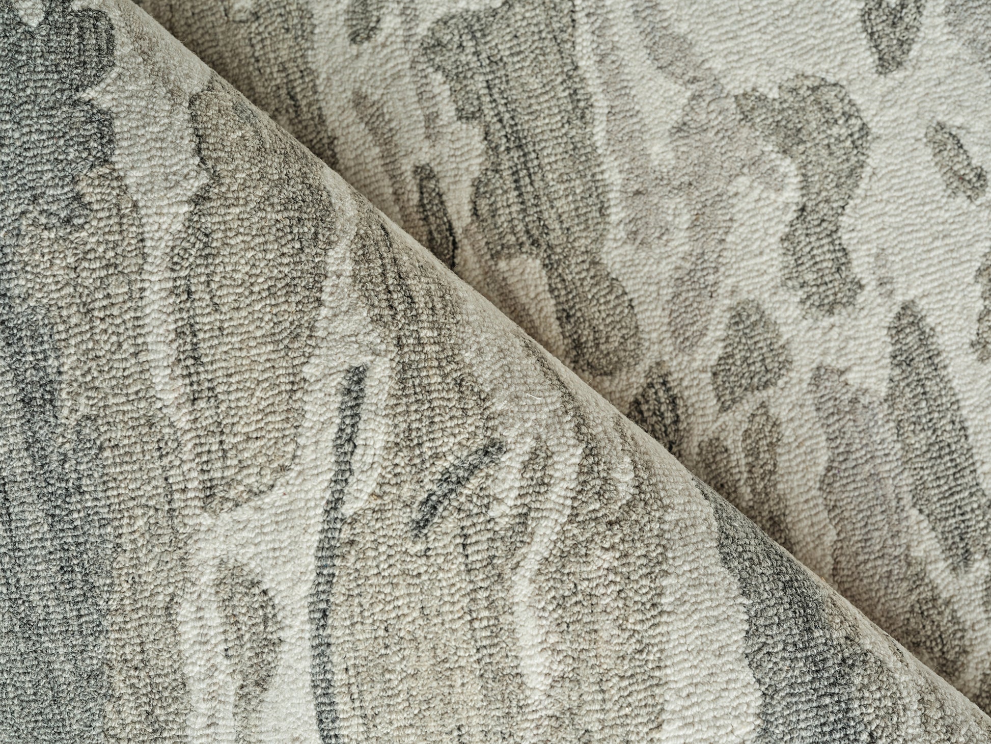 Beige and gray damask-patterned plush rug fabric, dense loop pile with abstract swirls, folded for display.
