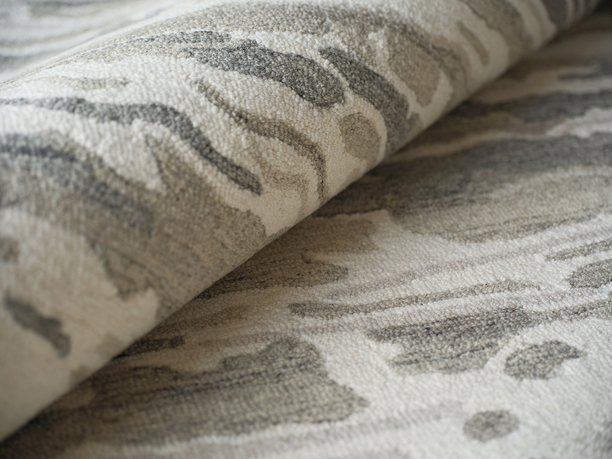 Beige and gray indoor hand-tufted rug with abstract marble-like pattern and soft, textured pile.