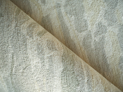 Close-up of soft beige-gray boucle-textured rug fabric, folded for cozy rug use.