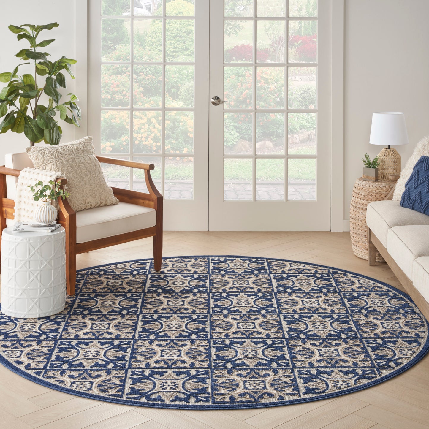 Round navy and beige patterned rug with intricate motif on light wood floor in a bright living room.