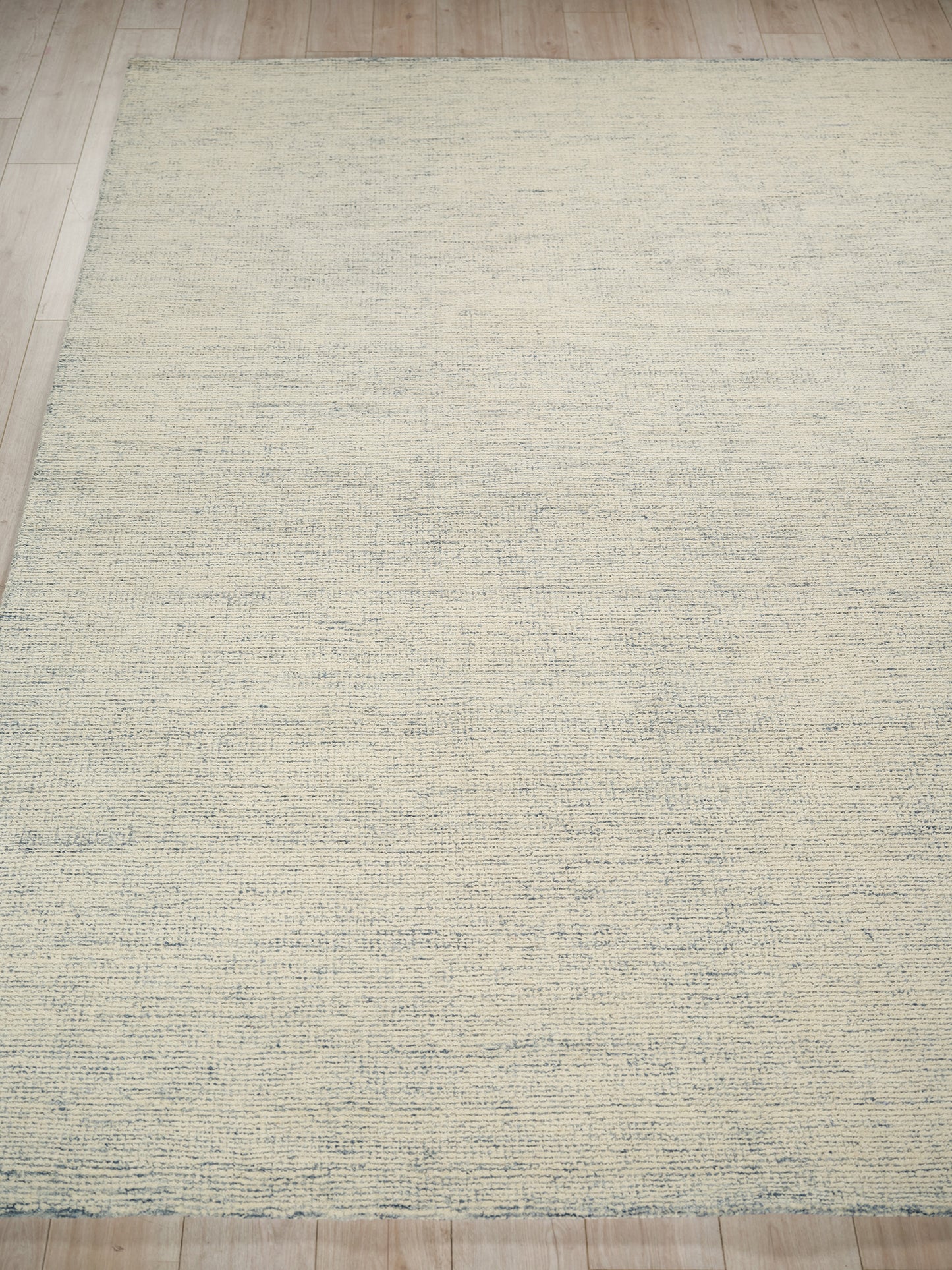 Rectangular beige rug with subtle blue-gray textured stripes on a light wood floor.